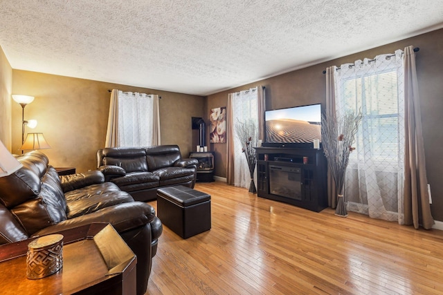 living area with a textured ceiling, a wealth of natural light, and light wood-style flooring