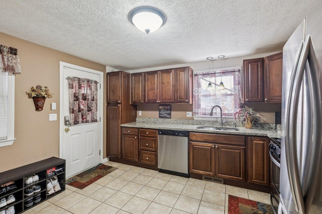 kitchen with visible vents, light stone counters, stainless steel appliances, pendant lighting, and a sink