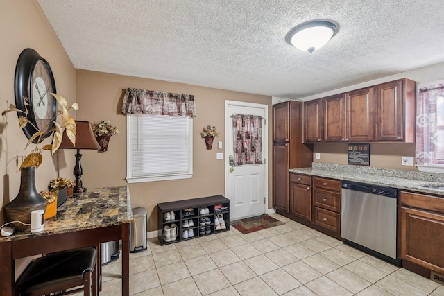 kitchen with light stone countertops, light tile patterned floors, dishwasher, and a textured ceiling