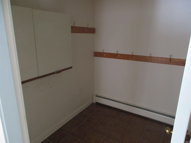 spare room with a baseboard heating unit and dark tile patterned flooring