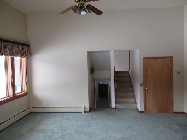 unfurnished living room with ceiling fan, carpet floors, and a towering ceiling