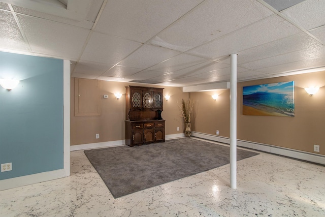 basement with a paneled ceiling and a baseboard radiator