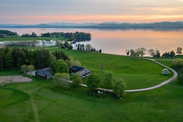 aerial view at dusk featuring a rural view and a water and mountain view