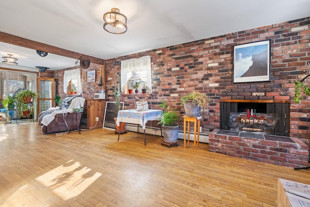 living room with beamed ceiling, a brick fireplace, hardwood / wood-style floors, and plenty of natural light