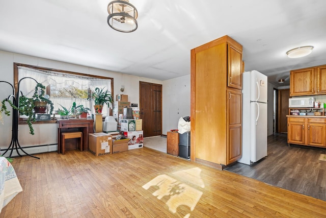 interior space featuring dark wood-type flooring, white appliances, and baseboard heating