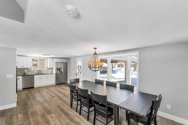 dining room with a healthy amount of sunlight, hardwood / wood-style flooring, sink, and a chandelier