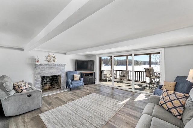 living room with a brick fireplace, wood-type flooring, and beam ceiling