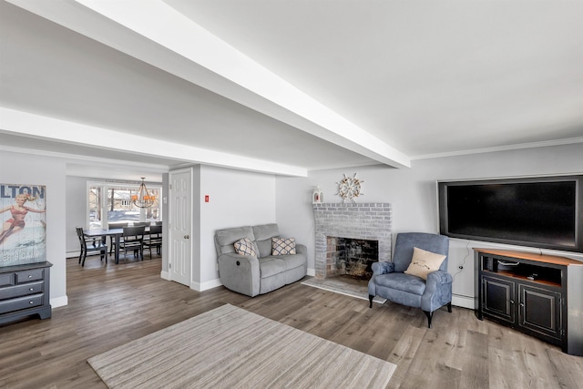 living room featuring baseboard heating, a brick fireplace, wood-type flooring, and beam ceiling