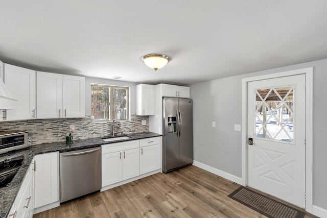 kitchen with white cabinets, dark stone countertops, stainless steel appliances, and sink