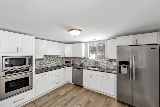 kitchen featuring custom exhaust hood, sink, stainless steel appliances, and white cabinetry