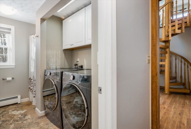 laundry room with baseboard heating, separate washer and dryer, and cabinets