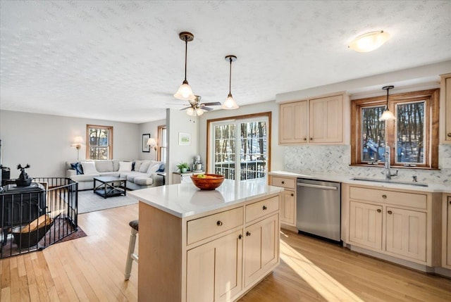 kitchen with light wood-type flooring, hanging light fixtures, sink, backsplash, and dishwasher