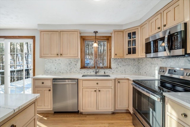 kitchen with light hardwood / wood-style flooring, light brown cabinetry, stainless steel appliances, pendant lighting, and sink