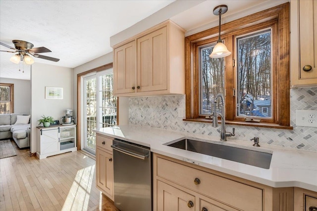 kitchen with light hardwood / wood-style flooring, stainless steel dishwasher, decorative light fixtures, decorative backsplash, and sink