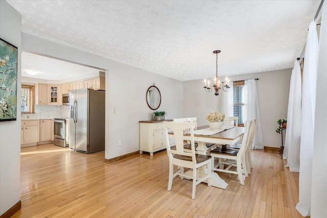 dining space with light hardwood / wood-style floors, a chandelier, and a textured ceiling