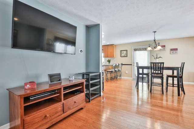 dining room with light wood-type flooring, an inviting chandelier, and a textured ceiling