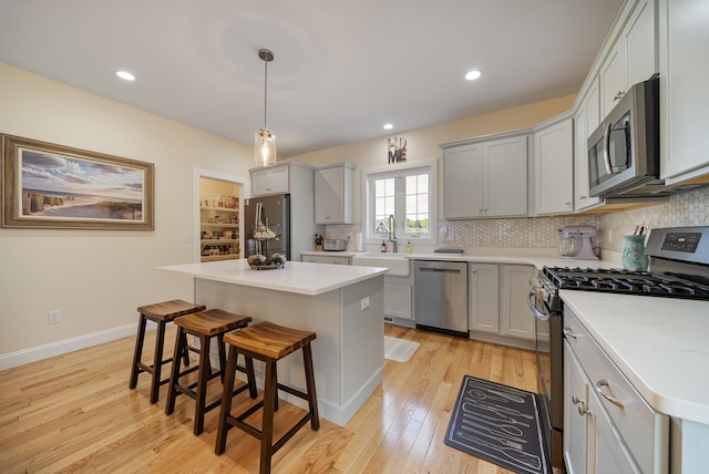 kitchen with sink, stainless steel appliances, a kitchen island, and decorative light fixtures