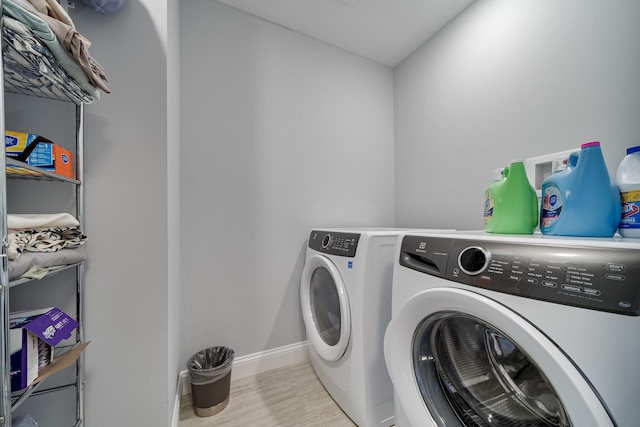 laundry area featuring washing machine and dryer and light hardwood / wood-style flooring