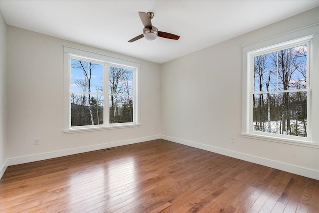 unfurnished room with ceiling fan, a wealth of natural light, and wood-type flooring