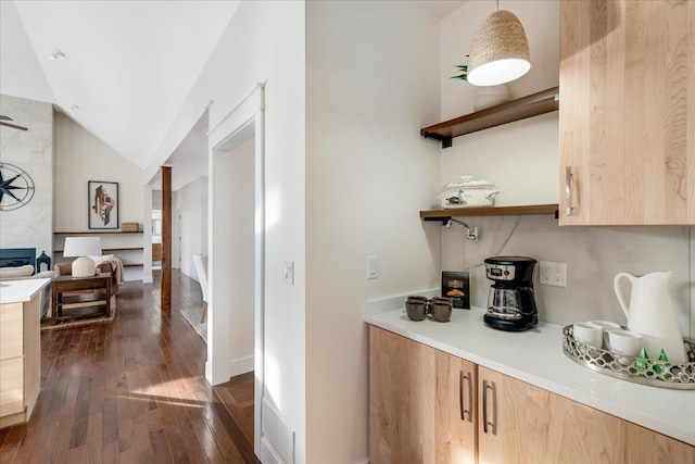 bar with light brown cabinetry, lofted ceiling, hanging light fixtures, and dark hardwood / wood-style floors