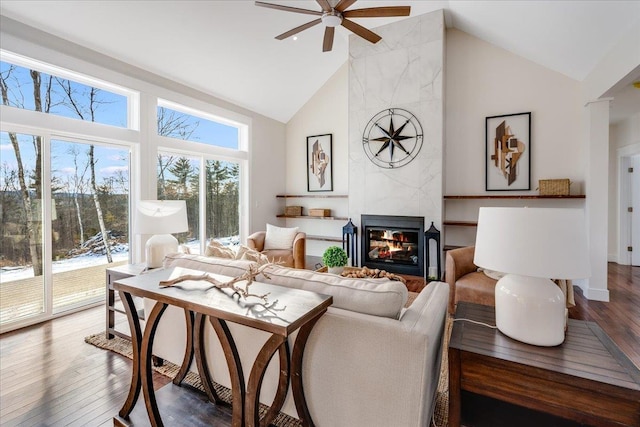 living room with ceiling fan, wood-type flooring, high vaulted ceiling, and a high end fireplace