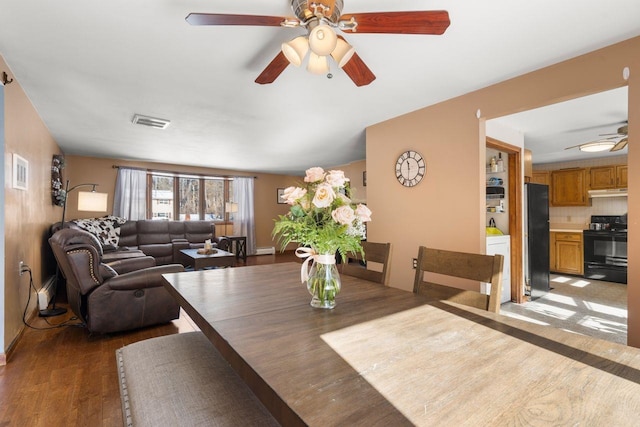 dining space with ceiling fan and dark wood-type flooring