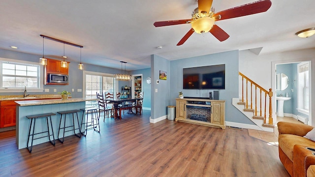 living room featuring sink, hardwood / wood-style flooring, ceiling fan, and baseboard heating