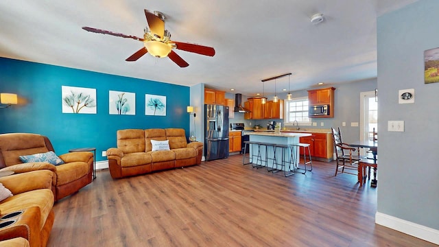 living room with sink, ceiling fan, wood-type flooring, and baseboard heating