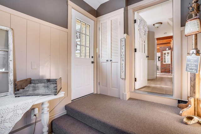 entryway featuring carpet and wood walls