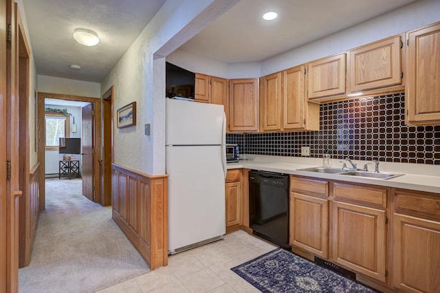 kitchen featuring wainscoting, black dishwasher, a sink, light countertops, and freestanding refrigerator