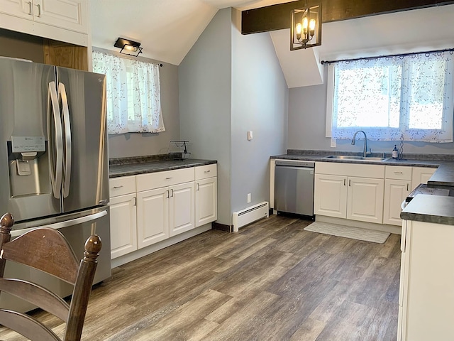 kitchen featuring appliances with stainless steel finishes, a baseboard heating unit, white cabinets, pendant lighting, and sink