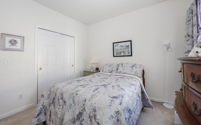 bedroom with baseboards, a closet, and light carpet