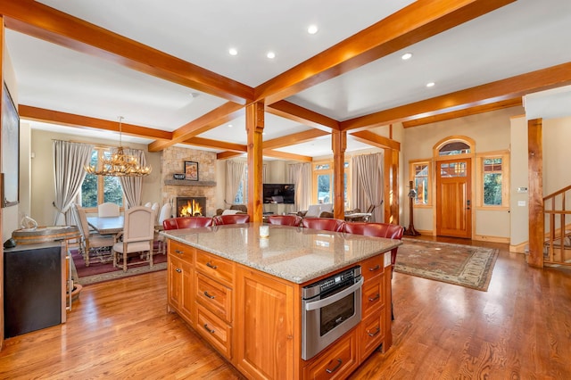 kitchen featuring open floor plan, stainless steel oven, decorative light fixtures, and light wood-style floors