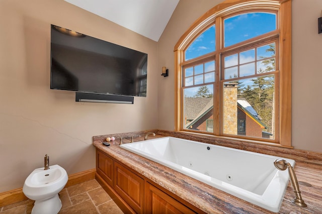 full bath with baseboards, stone tile flooring, a tub with jets, a bidet, and vaulted ceiling