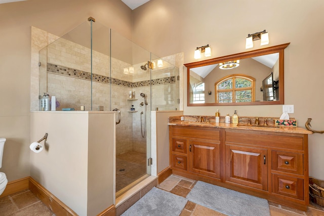 full bathroom featuring double vanity, vaulted ceiling, a sink, and a stall shower