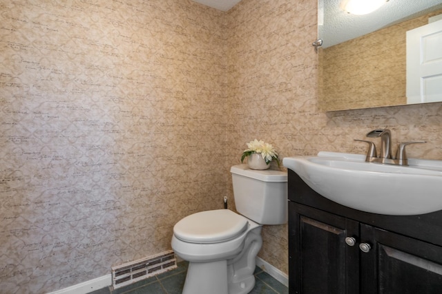 half bathroom featuring baseboards, visible vents, toilet, vanity, and tile patterned floors