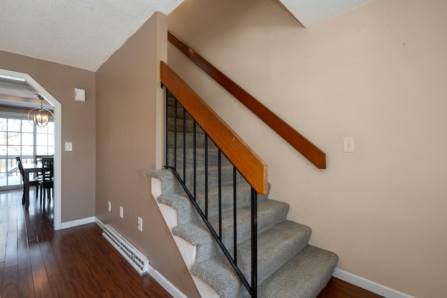 stairway with baseboards, a notable chandelier, arched walkways, and wood finished floors