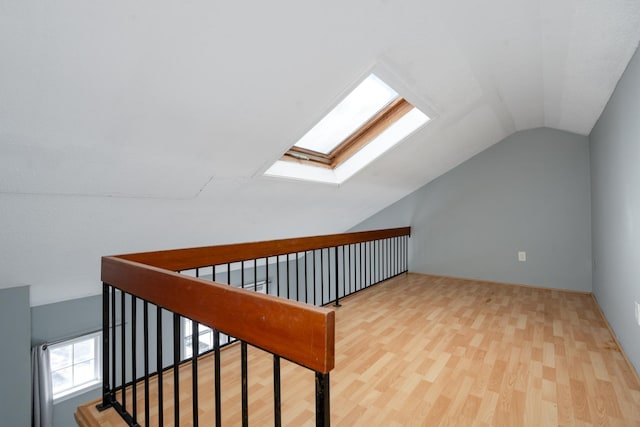 bonus room featuring light wood finished floors and lofted ceiling with skylight