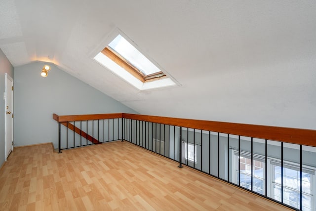 additional living space featuring wood finished floors and lofted ceiling with skylight