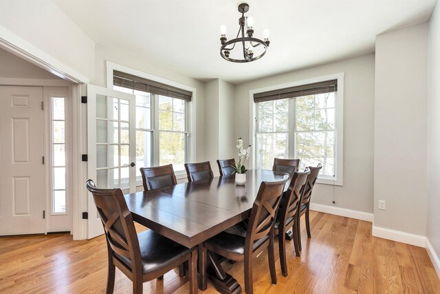 dining room with a wealth of natural light, baseboards, a notable chandelier, and light wood-type flooring