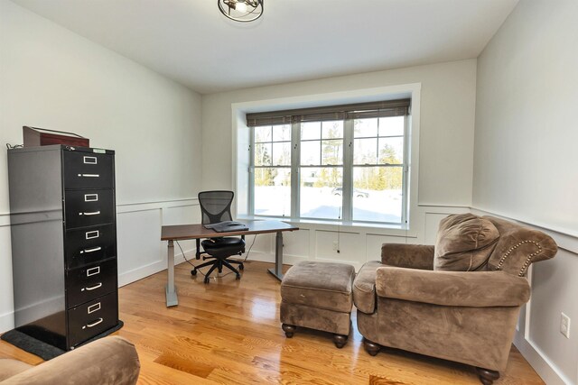 office space featuring wainscoting, light wood-style floors, and a decorative wall