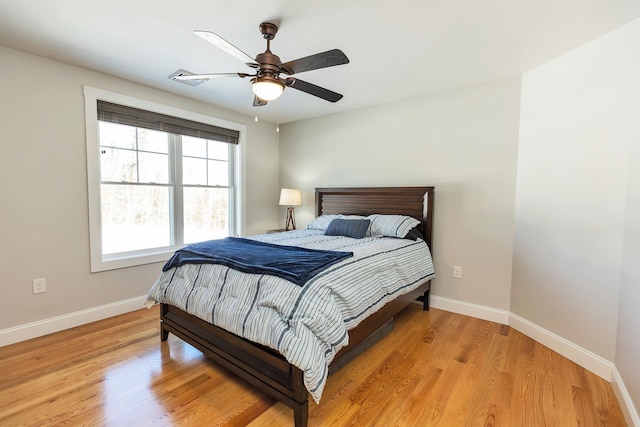 bedroom with baseboards, a ceiling fan, light wood finished floors, and visible vents