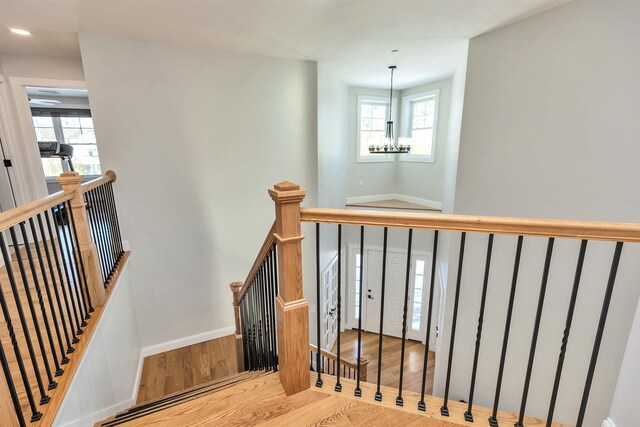 stairs with baseboards, an inviting chandelier, wood finished floors, and recessed lighting