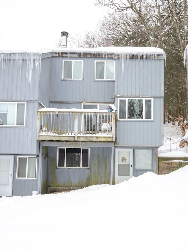 snow covered house featuring a balcony