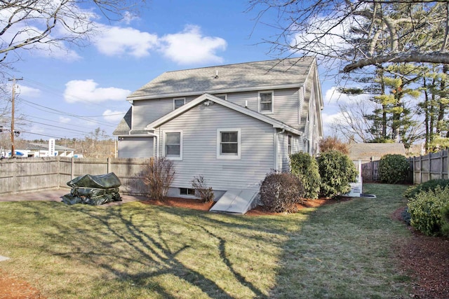 rear view of house featuring a lawn and a fenced backyard