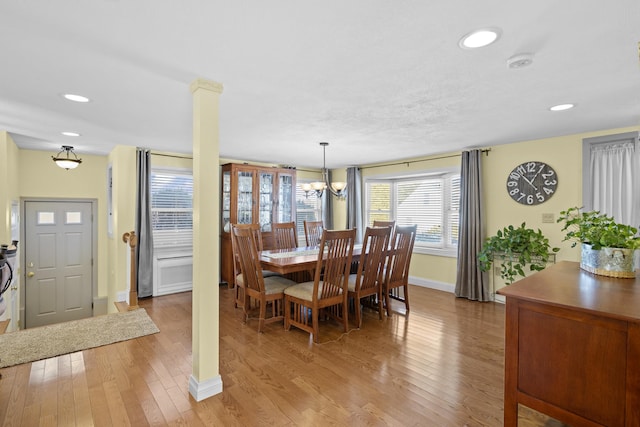 dining area with decorative columns, light wood finished floors, recessed lighting, an inviting chandelier, and baseboards