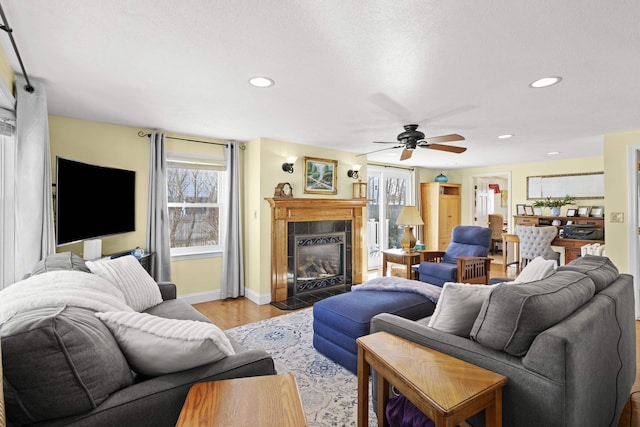 living area featuring light wood-style floors, a tile fireplace, baseboards, and recessed lighting