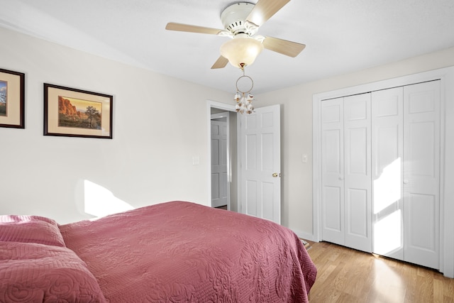 bedroom with light wood-style flooring, baseboards, ceiling fan, and a closet