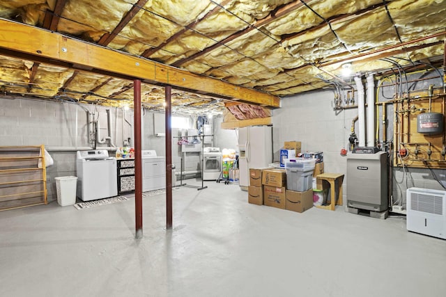 basement featuring white refrigerator with ice dispenser, a heating unit, and washer and dryer