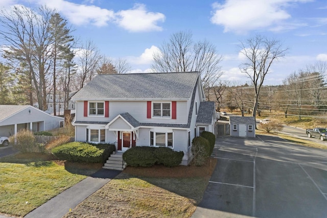 traditional-style home featuring a shingled roof and an outbuilding